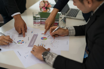 Group of businesspeople at meeting discussing ideas while looking at the graphs and charts