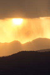 Setting sun behind a rain shower near Lijiang in Yunnan, China