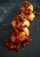 Baked jacket potatoes topped with red kedney beans in tomato sauce and chives served on stone board