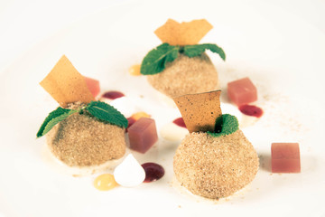 Plum dumplings with cinnamon, white chocolate and vanilla sauce on a white background