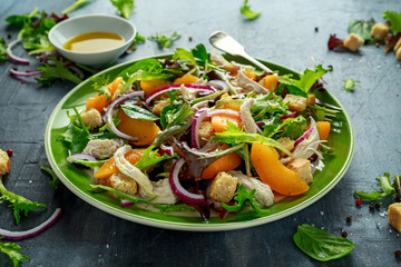 Fresh salad with chicken breast, peach, red onion, croutons and vegetables in a green plate. healthy food