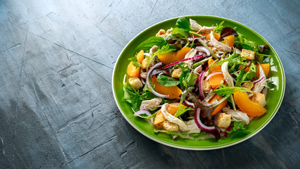 Fresh salad with chicken breast, peach, red onion, croutons and vegetables in a green plate. healthy food