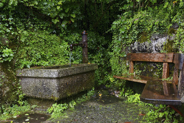 Stony fountain with mechanical water pump and bench in Hallstatt
