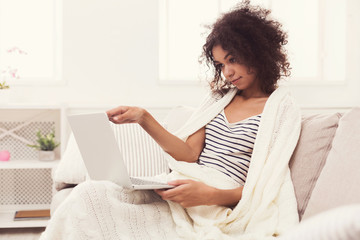Fototapeta premium Young girl with laptop sitting on beige couch