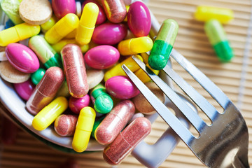 health care and wellness - diet pills and loosing weight - various tablets in a pot with forks
