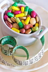health care and wellness - diet pills and loosing weight - various tablets in a pot with measuring meter