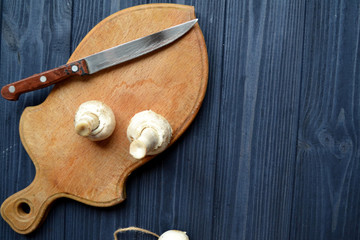 Mushrooms on the dark blue wooden desk. Cooking champignons.
