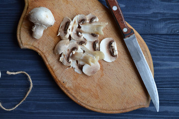 Mushrooms on the dark blue wooden desk. Cooking champignons.
