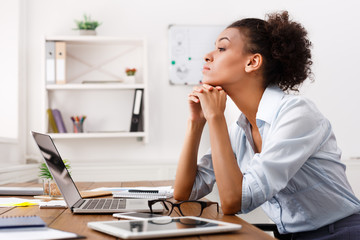 Thoughtful woman working on laptop at office