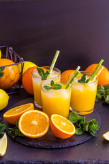 Fototapeta na wymiar glass jar of fresh orange juice with fresh fruits on dark table.