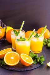 glass jar of fresh orange juice with fresh fruits on dark table.