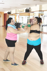 Fototapeta na wymiar Trainer helps her friend for doing a stretch