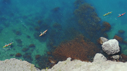 Top view from the rock of kayaks kayaking and enjoying the tropical crystal clear turquoise blue waters in paradise