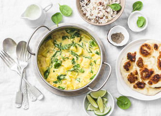 Vegetarian chickpea, spinach, potato curry pan and naan flatbread on white background, top view. Indian healthy food concept