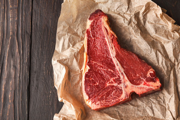 Raw t-bone steak on craft papper on dark background