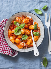 Potato gnocchi with tomato sauce, basil and parmesan on a blue background, top view. Traditional italian food pasta