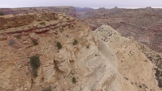 Aerial view flying past man standing at overlook on cliffs edge at the Wedge in the San Rafael Swell.