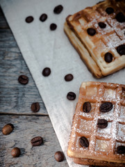 Soft Viennese Belgian waffles with powdered sugar and coffee beans on rustic wooden background