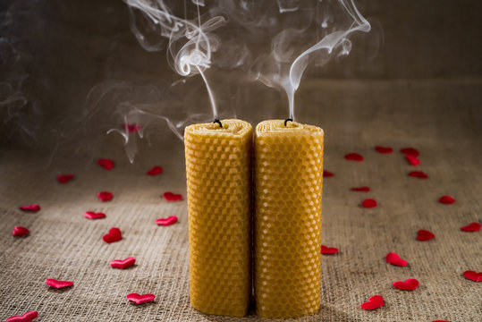 A pair of extinct candles on a background with hearts.
