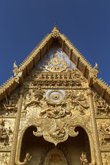 Fototapeta na wymiar The gable apex of golden temple on blue sky background