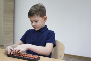 Mental arithmetic school. Boy counts with abacus in "soroban" class. Japanese abacus. Concept of back to school. student siting at the desktop.  copy space for text.