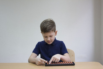 Mental arithmetic school. Boy counts with abacus in 