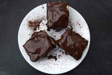 Appetizing chocolate cakes are located on a white plate close-up.