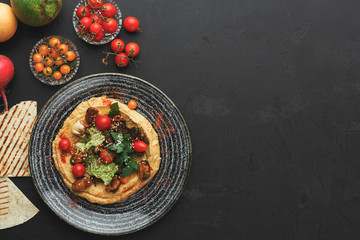 Hummus with vegetables and seafood on black background