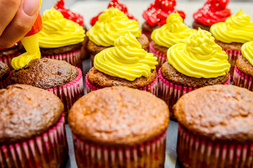 The process of applying yellow oil cream on muffins.
