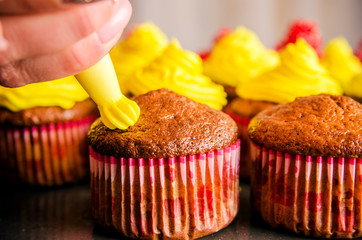 The process of decorating muffin with confectionery cream.
