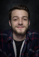 Portrait of a young man with a beard on a dark background.