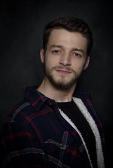 Portrait of a young man with a beard on a dark background.