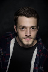 Obraz premium Portrait of a young man with a beard on a dark background.
