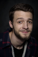 Portrait of a young man with a beard on a dark background.