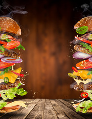 Big tasty burger with flying ingredients. - obrazy, fototapety, plakaty