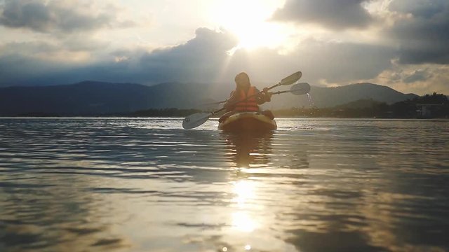Happy smiling couple kayaking along the sea at beautiful summer sunset. Tourists paddling kayak, teamwork, togetherness. Slow motion. 1920x1080