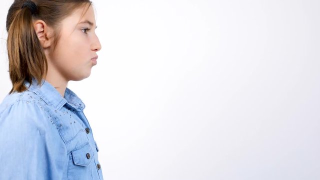 Slow motion portrait of young cute little girl making silly faces at the second part of the frame on gray background