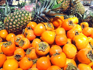 Many fruits persimmon and pineapples lying in the supermarket