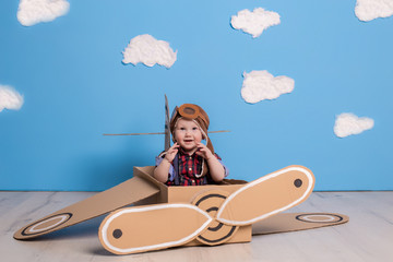 Little child girl in a pilot's costume is playing and dreaming of flying over the clouds.