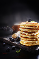 Stack of pancakes with fresh berries served on old black board . Selective focus.