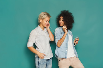 Two women listening music and sharing earphones