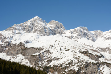 Winter landscape at early morning in Austria with snow, wooden buildings, blue sky and copy space.