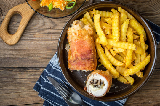 Fried chicken breast stuffed with mushrooms and cheese wrapped in ham served with fries and salad.