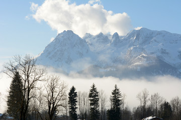 Winter landscape at early morning in Austria with snow, wooden buildings, blue sky and copy space.