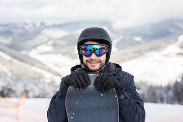 Fototapeta na wymiar Snowboarder in ski suit and helmet with snowboard on mountains