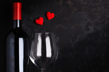 Bottle and glass of wine With 2 red hearts On the old black rusty floor.