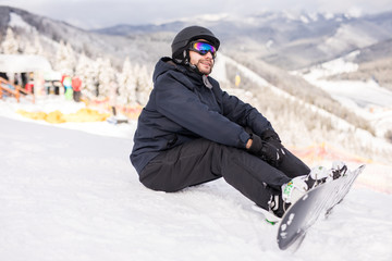 Snowboarder sitting on a ski slope before ride