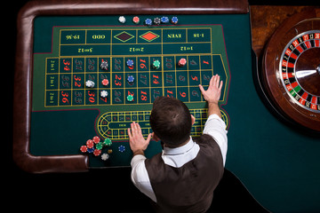 Top view of the casino croupier and the green roulette table. Ga