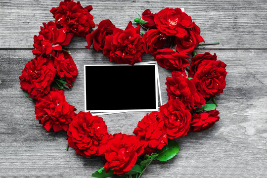 red rose flowers heart shaped with blank photo frame on rustic wooden background