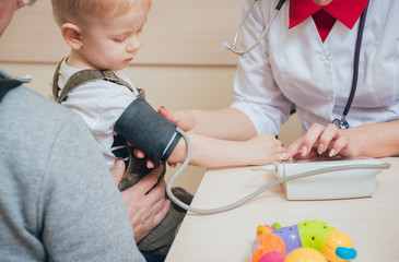 Doctor measuring blood pressure of a child. - Powered by Adobe